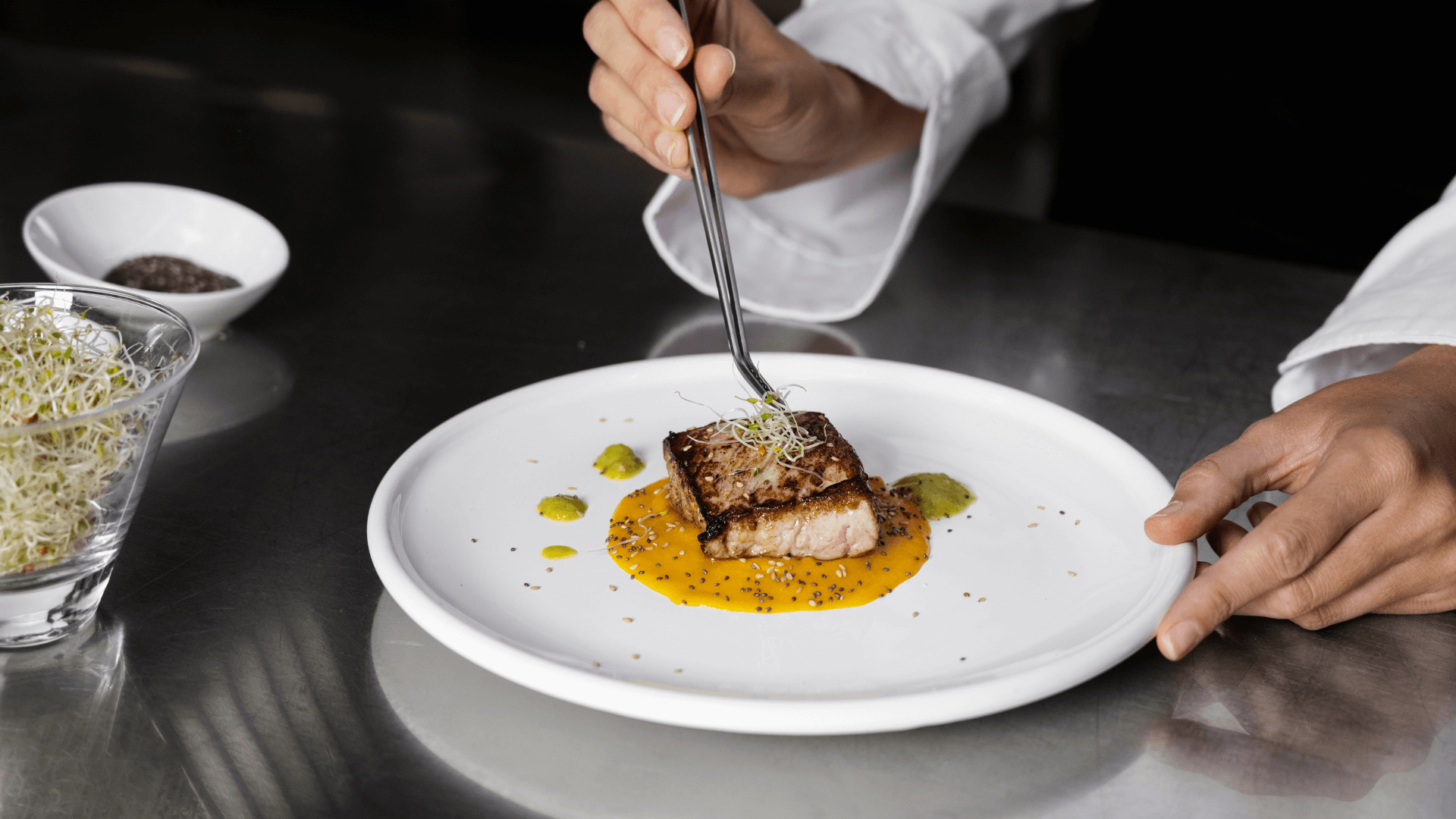 A chef adds herbs to the to of a piece of fish.