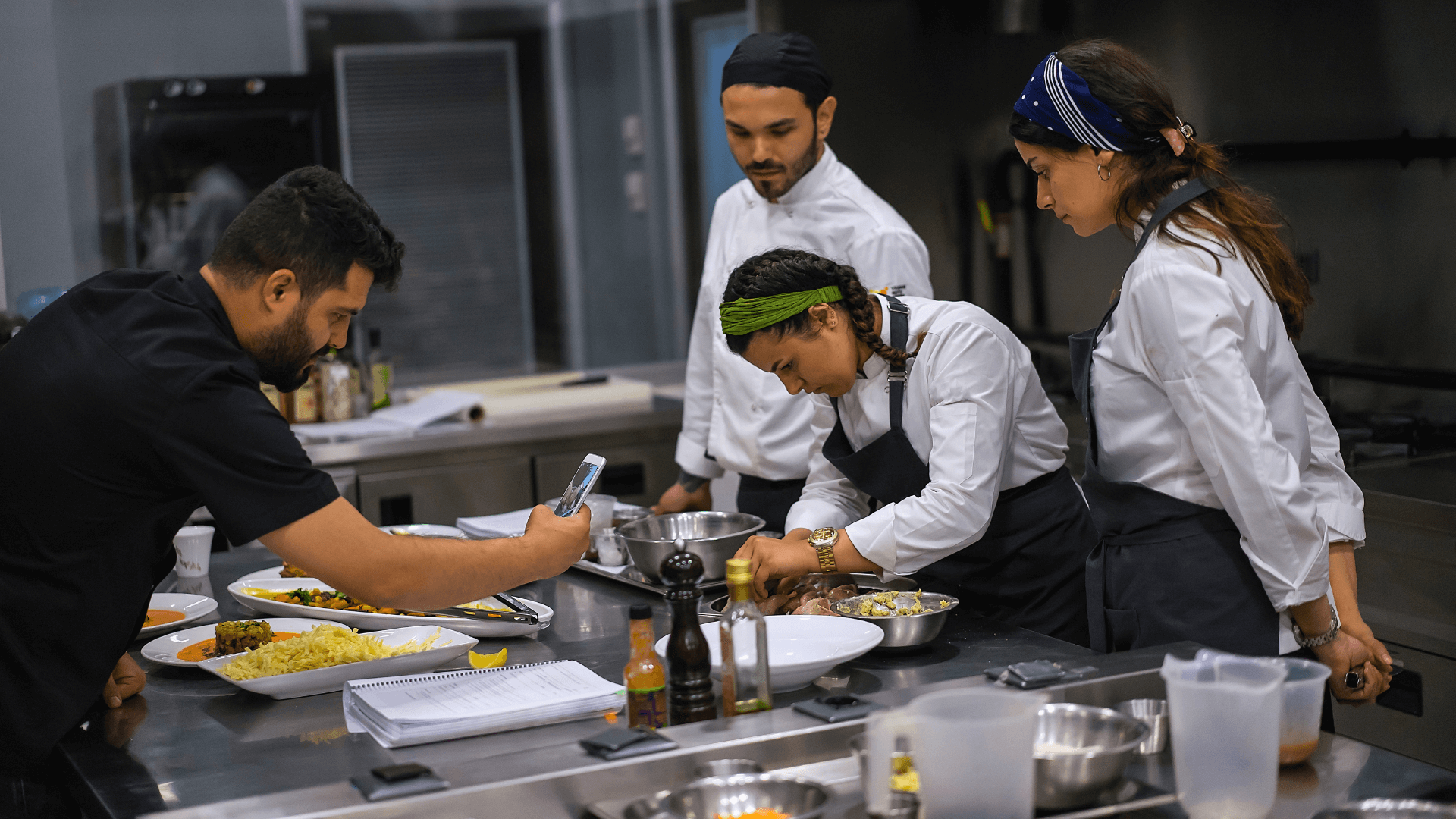 4 chefs in the kitchen preparing a dish.