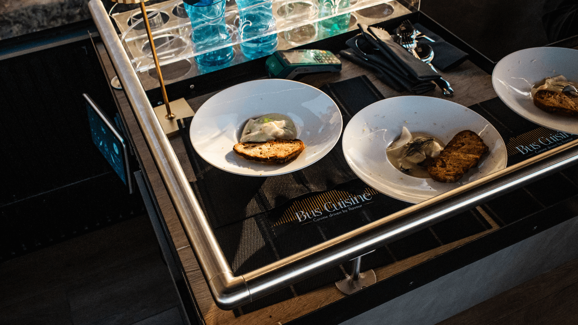 Two plates on a table with the Bus Cuisine logo underneath