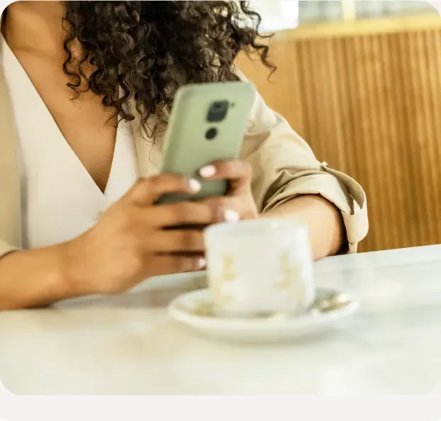 Person reading newsletter on phone at a cafe